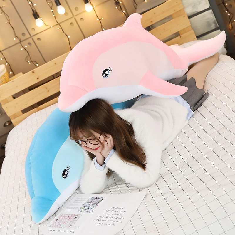 Delphin-Plüschtier für Mädchen auf einem Bett mit liegender Tochter