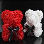 Zwei Teddybären aus künstlichen Blumen, einer ist rot und der andere weiß, sie befinden sich in einem schwarzen Raum