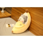 Geschälte Banane Plüschtier mit einem grauen Shiba Inu darin auf einem grauen Bett und einem gegen eine Wand in Holzfarbe mit einem Buch neben ihm
