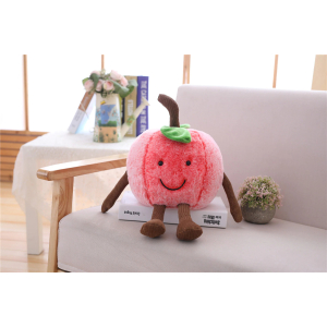 Lächelndes rosa Kirschplüschtier auf einem Buch und einem grauen Sofa neben einer kleinen Pflanze und einem Couchtisch mit Büchern im Hintergrund